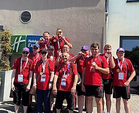 Eine Gruppe von Menschen in Sportkleidung posiert für ein Foto. Sie zeigen Medaillen.