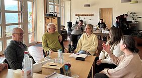 Menschen sitzen am Tisch und unterhalten sich