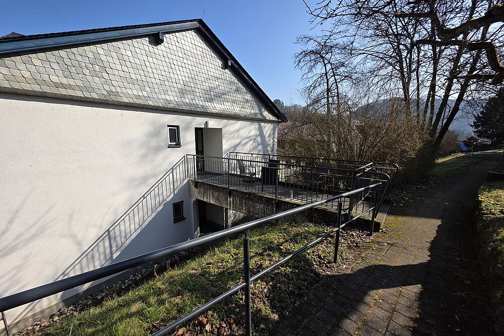 Seite eines Hauses mit einer Terrasse. 