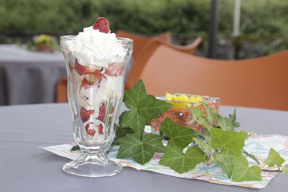 Ein Erdbeerbecher mit Sahne, Eis und frischen Erdbeeren.