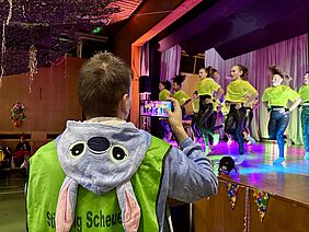 Junger Mann macht ein Foto mit dem Mobiltelefon von einer Tanzgruppe