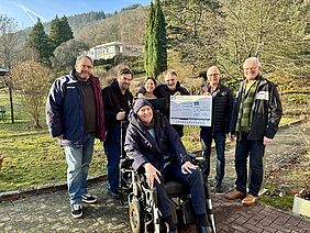 Eine Gruppe Menschen präsentiert einen Spendenscheck