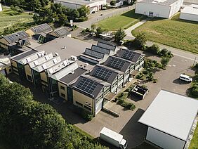 Auf dem Dach eines Werkstattgebäudes sind aus der Vogelperspektive Solarmodule zu sehen.