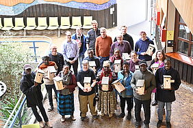 Eine Gruppe von Menschen steht zusammen und präsentiert Nistkästen.