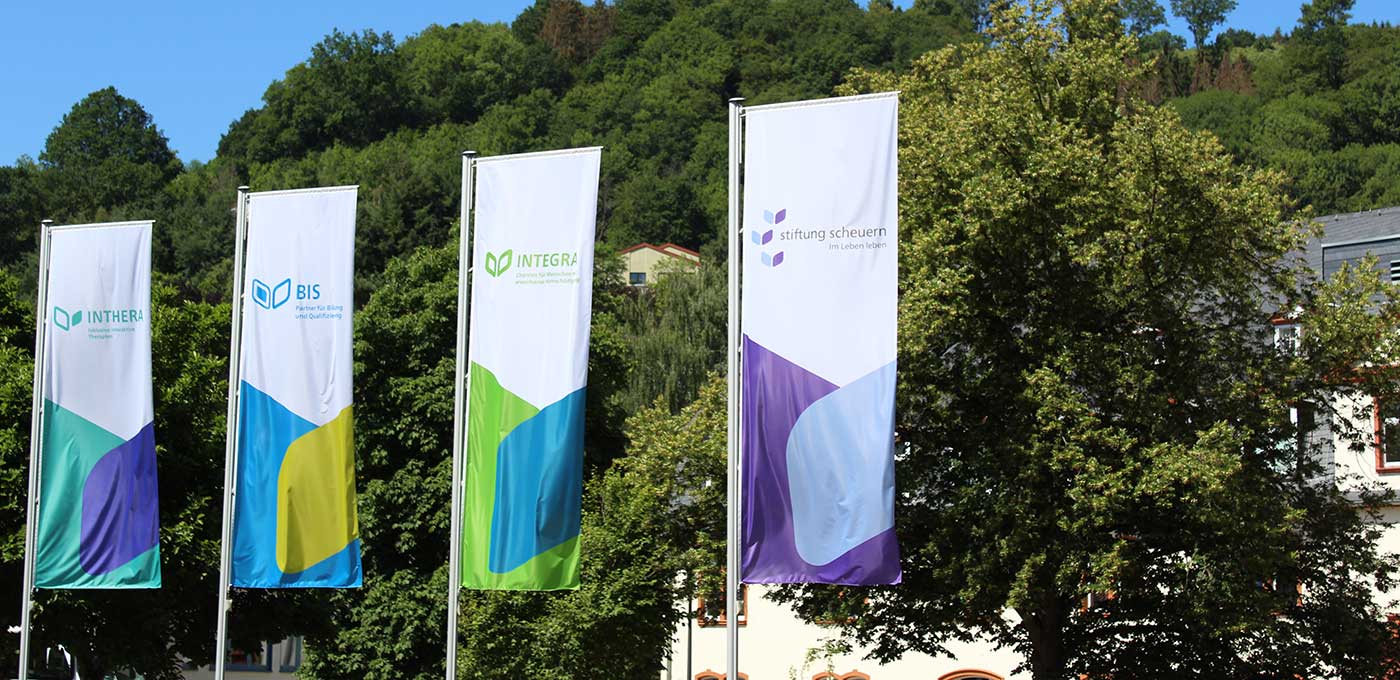Fahnen mit Logo der Stiftung Scheuern und dortiger Dienstleistungen der Behindertenhilfe.